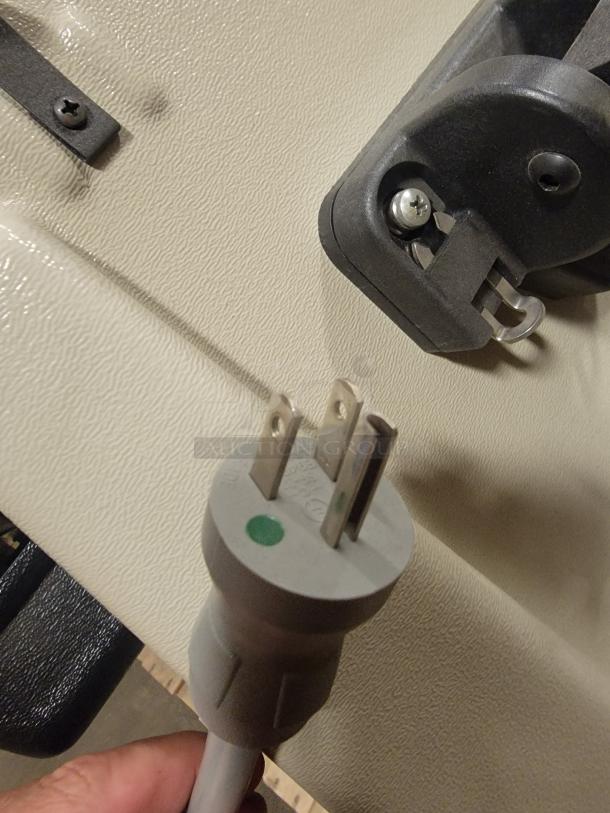 Midmark 75L Medical Exam Chair power plug detail on beige textured surface, showing power connectivity feature.