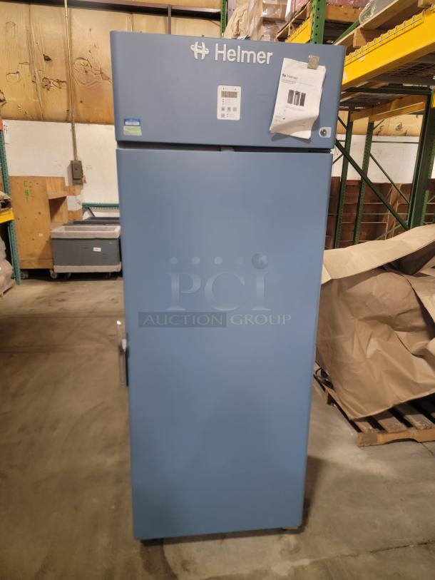 Helmer HLF120 Horizon Series medical-grade freezer, blue, with visible labels and papers on the door.