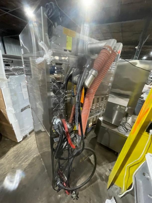 Industrial-grade machinery with wires and cooling fans, in used condition. Reflective metal surface with visible labels.