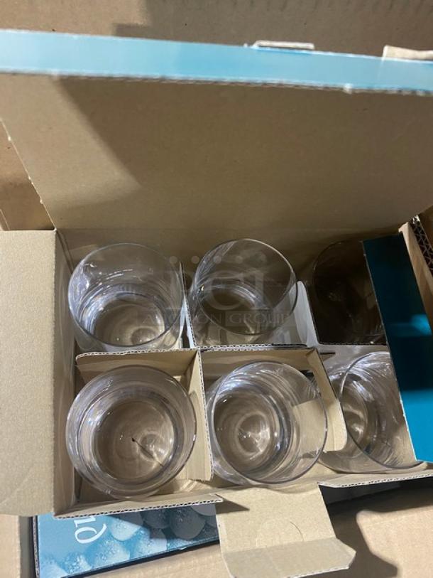 Set of six clear glass tumblers in original packaging, new condition, with protective cardboard dividers.