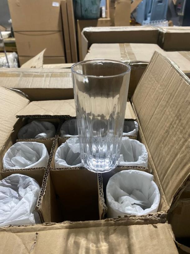 Box of clear glass tumblers with ribbed design, new in packaging. Eleven glasses wrapped in tissue paper, one displayed.