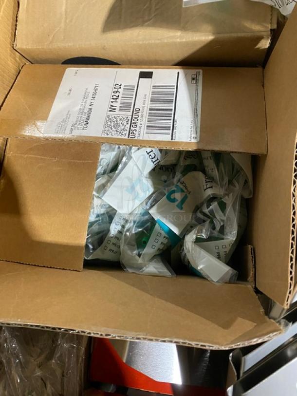 Open cardboard box containing several sealed plastic packages labeled with "12" and "Lot." Visible shipping label on box lid.
