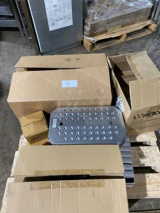 Metal footplate with rivets, in good condition, surrounded by opened cardboard boxes on a pallet. Some boxes are labeled with "Vince."