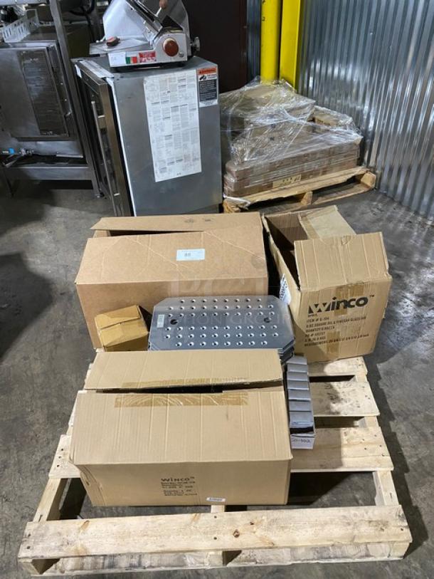 Boxes of Winco kitchen equipment on a pallet, including a perforated metal sheet. Some boxes unopened, indicating new condition.