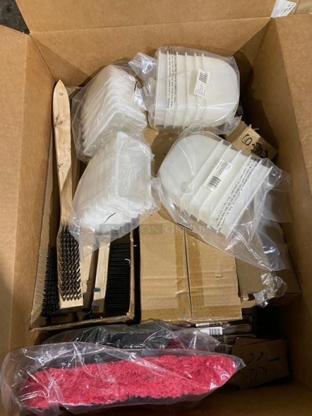 Box of assorted cleaning supplies, including plastic dustpans, scrub brushes, and sponges, all in new condition.