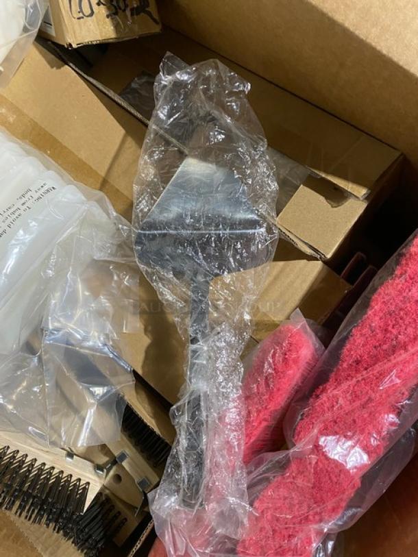 Metal grill scraper in plastic wrap, boxed, new condition, with cleaning pads and springs nearby.