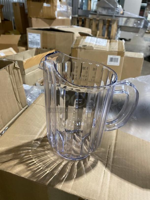 Clear plastic pitcher with spout and handle, ribbed design, like-new condition, shown among cardboard boxes.