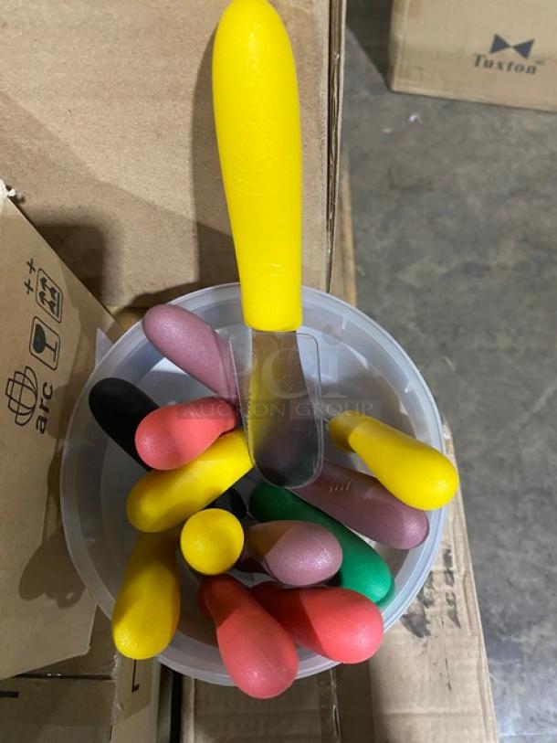 Container with assorted colorful ice cream scoops and a yellow-handled spreader. Items appear in good condition.