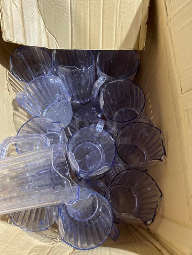 Box of clear plastic pitchers, in new condition, featuring ribbed design and sturdy handles.