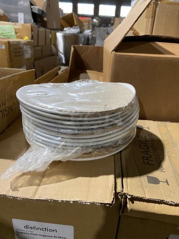 Stack of new 20.26 cm organic plates wrapped in plastic, on top of labeled boxes in warehouse.