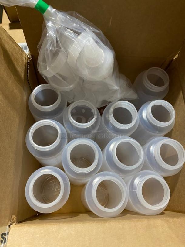 Box of clear plastic bottles, new, with separate lids in plastic. Ideal for storage or packaging. Quantity visible: approx. 15.