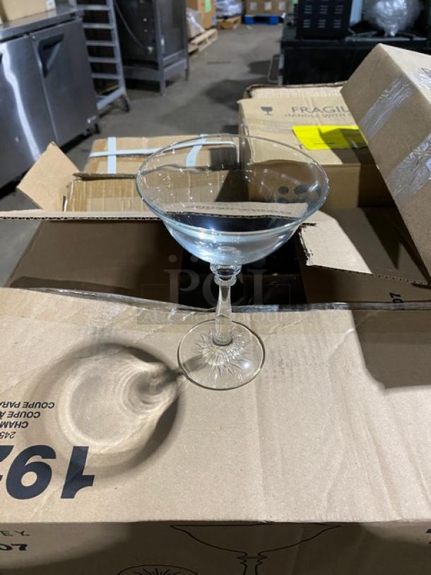 Crystal coupe glass with etched pattern displayed on a cardboard box, showcasing its elegant design and clarity.