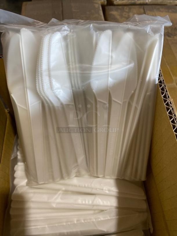 Box of sealed white plastic cutlery sets, individually wrapped, containing knives, forks, and spoons. New condition.
