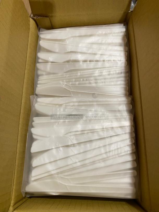 Box of individually wrapped disposable white plastic knives, arranged neatly, in new condition.