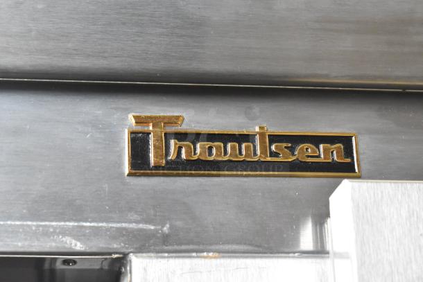 Traulsen G20010 stainless steel cooler badge, highlighting brand in gold lettering on a black background.
