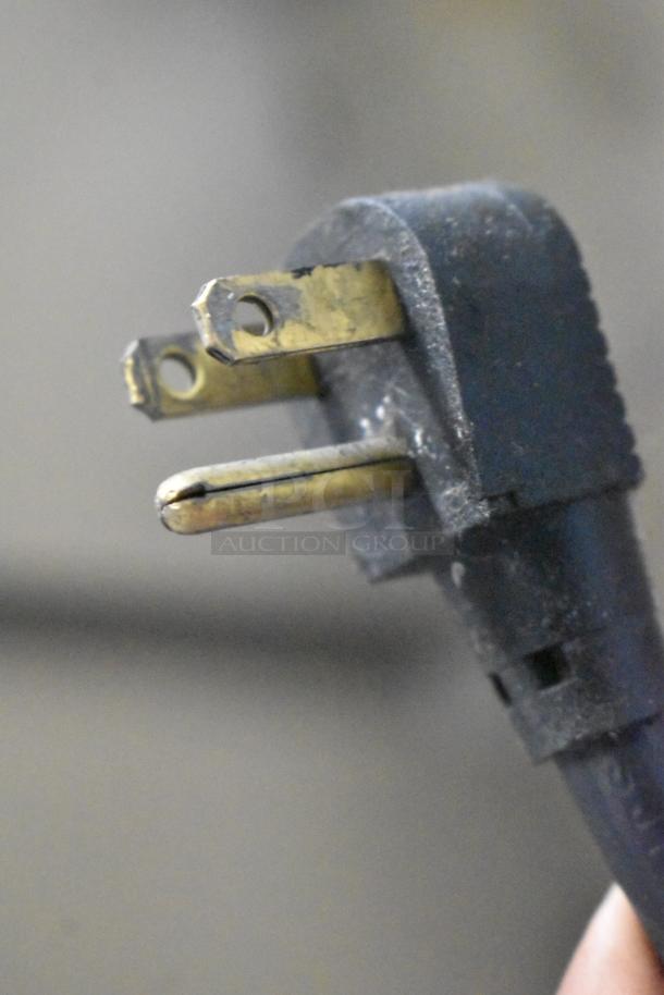 Close-up image of a power cord plug for the Traulsen G20010 cooler, showing three prongs and signs of wear.