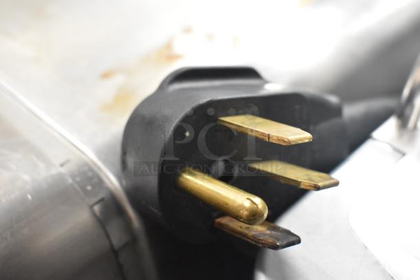 Close-up of a plug from the 2020 Bunn ICB TWIN SH Commercial Coffee Machine, showing three brass prongs and a black casing.