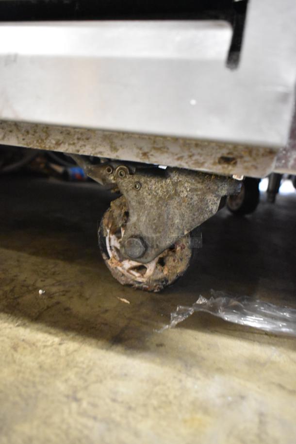 Arctic Air ARCB60CZ stainless steel chef base caster, showing signs of heavy use and dirt accumulation.