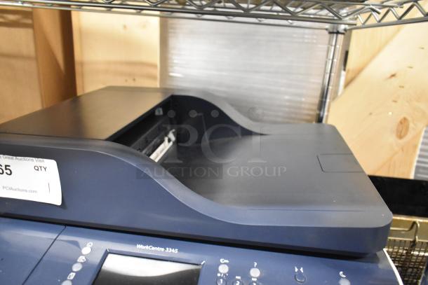 Xerox WorkCentre 3345 printer copier, dark gray, touchscreen controls, visible label, excellent condition, on metal shelf.