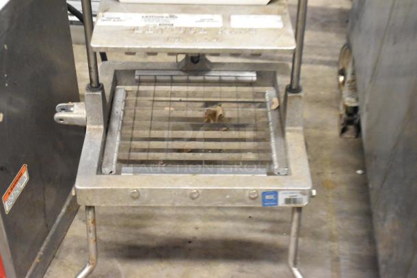 Metal countertop lettuce head cutter with grid blade, sturdy frame, visible usage wear, ideal for commercial kitchens.