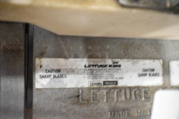 Metal countertop lettuce head cutter with a caution label indicating sharp blades; brand: Lettuce King, used condition.