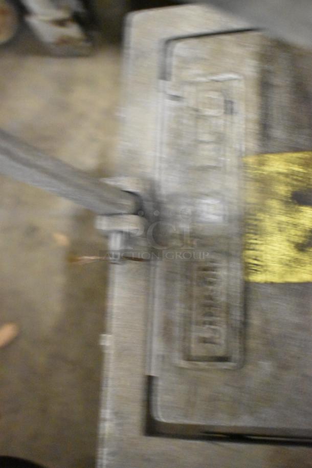 Metal countertop lettuce head cutter with visible wear. Features a sturdy handle and base. No visible brand markings.