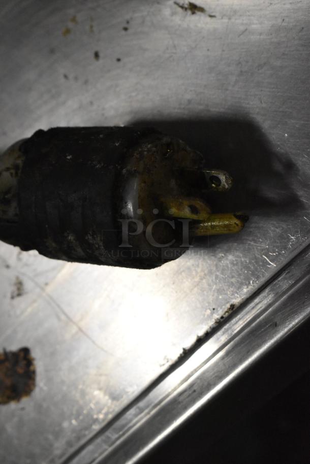 A worn, electrical plug on a metal surface, possibly for wiring inspection or replacement.