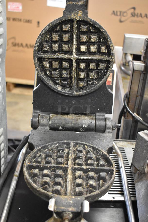 Metal commercial countertop waffle maker, 115 volts, 1 phase. Visible wear with waffle grid patterns, ideal for heavy use.