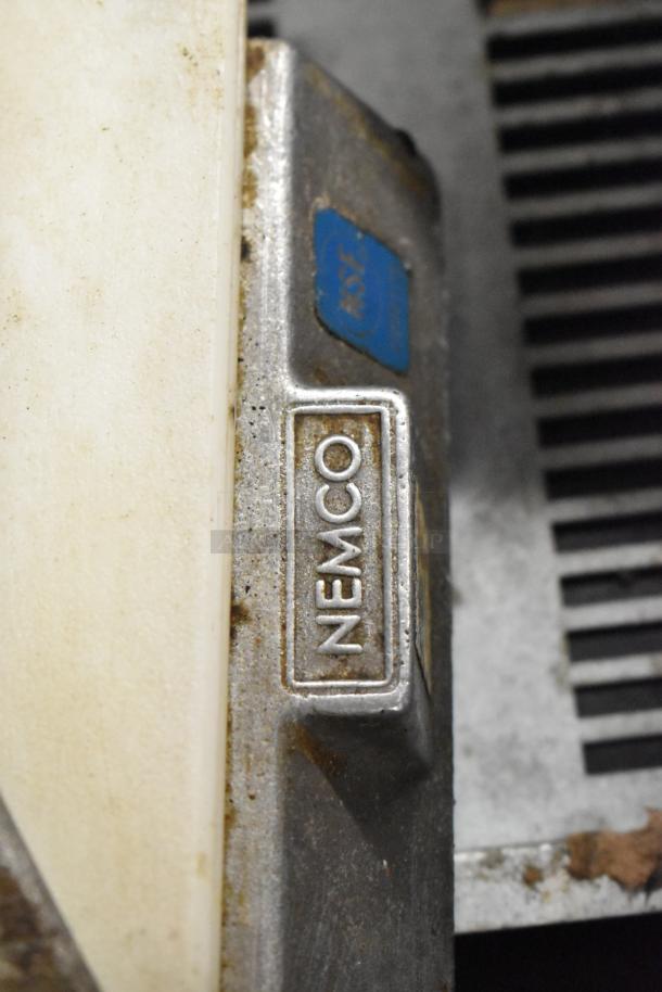 Nemco tomato slicer with visible brand marking, metal housing, and slight wear, crucial for efficient kitchen prep.