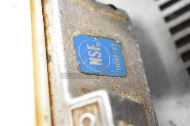 Close-up of a Nemco tomato slicer showing an NSF certification label with number D046173, indicating safety compliance.