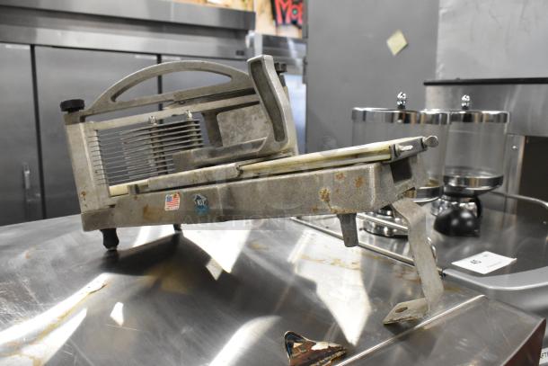 Nemco Tomato Slicer with metal frame and NSF sticker, showing signs of wear, placed on a stainless steel surface.