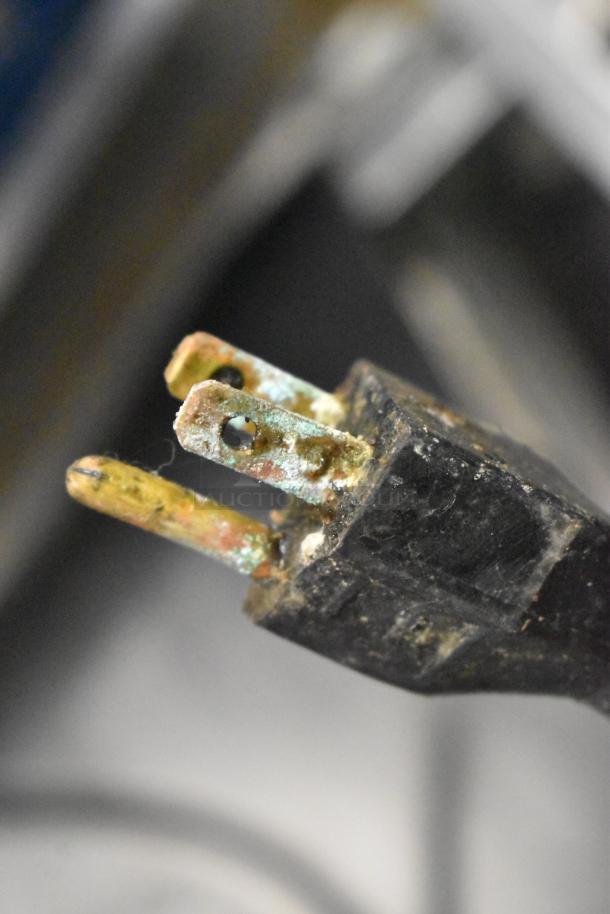 Close-up of a corroded electrical power plug, three-pronged.
