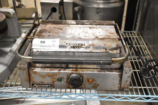 Adcraft SG-811 metal countertop panini press, 120 volts, showing signs of rust and wear. Includes caution hot label.