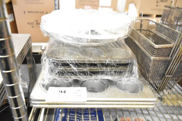 Tier lot of metal fry baskets and muffin baking pans wrapped in plastic, shows auction tag number 94. Items appear in good condition.