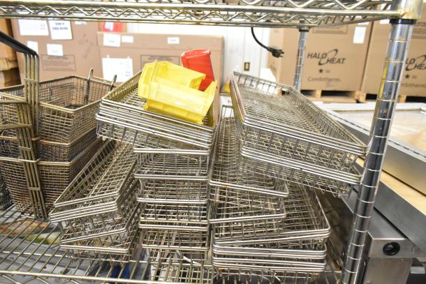 Tiered lot of metal fry baskets and baking pans, in good condition, displayed on a metal rack.