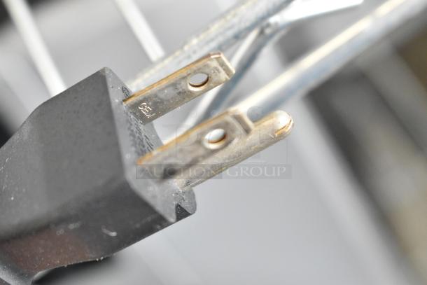 Close-up of a Keurig K150 coffee machine power plug, highlighting its two-prong design and slight wear.