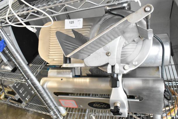 Globe stainless steel commercial countertop meat slicer, 115 volts, 1 phase, in good condition, mounted on metal shelving.