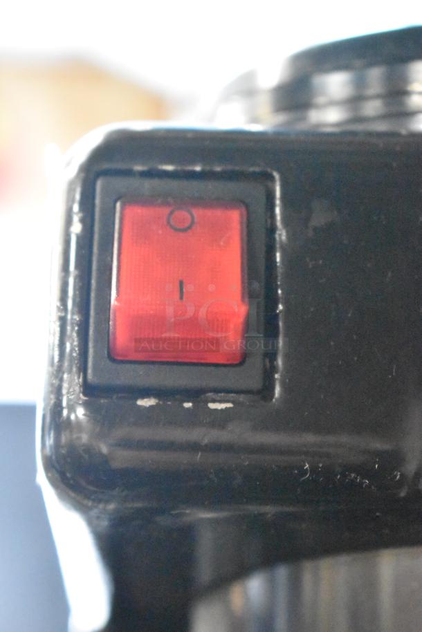 Red power switch on a metal commercial countertop espresso bean grinder, 115 volts, 1 phase, slight wear visible.