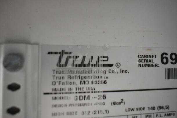 True GDM-26 metal cooler label showing model and serial number details. Made in USA, 115 volts, 1 phase, poly coated racks.