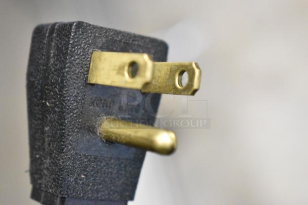 Close-up of a power plug for a True GDM-26 cooler, showing the prongs and textured casing detail.