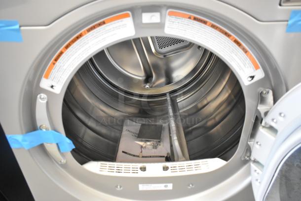 Brand new Crossover 2.0 metal front load washer, interior view, minor cosmetic scratches, includes manual and accessories.