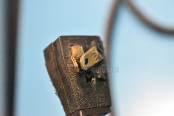 Damaged electrical plug showing frayed edges and exposed prongs, needing replacement or repair.