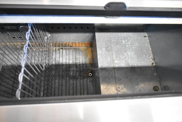 2017 True TD-65-24 metal back bar bottle cooler, interior view. Two sliding lids, on casters, shows signs of rust. 115V, 1 Phase.