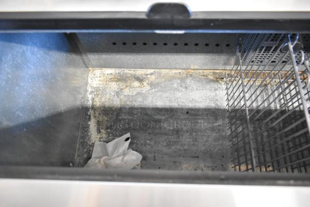 2017 True TD-65-24 metal commercial back bar cooler, interior view showing wear and debris. Features 2 sliding lids and commercial casters.