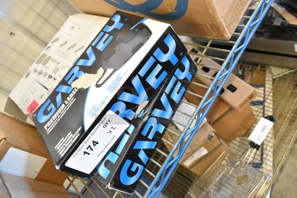 Two Garvey G2212-08008 labelers in original packaging on a metal shelf. Boxes show minor scratches, label indicates quantity of two.