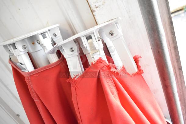 Two Coca Cola red patio umbrellas with fringed edges in fair condition, featuring sturdy white metal frames.