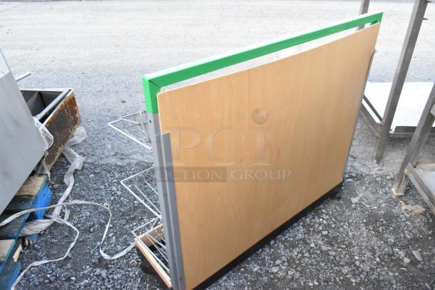 Wooden merchandising rack on casters, featuring metal wire shelving and a vibrant green accent on top, shown outdoors.