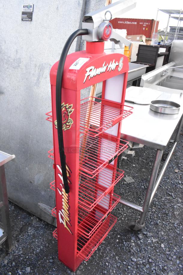 Red metal shelving unit with decorative fire extinguisher top, featuring "Flamin' Hot" graphics, multiple wire shelves.