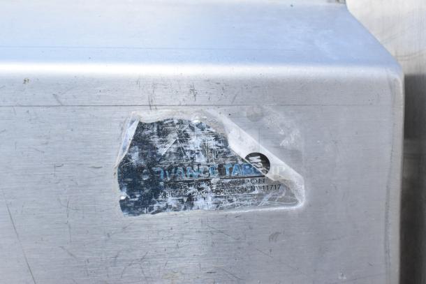 Stainless steel 3 bay sink with dual drain boards, faucet, and handles. Worn Advance Tabco label indicating model 4-1-1 17.