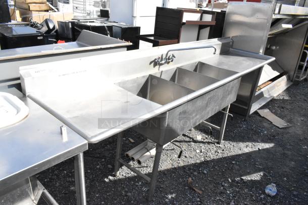 Stainless steel 3 bay sink with dual drain boards, faucet, and handles, in good condition, suitable for commercial use.